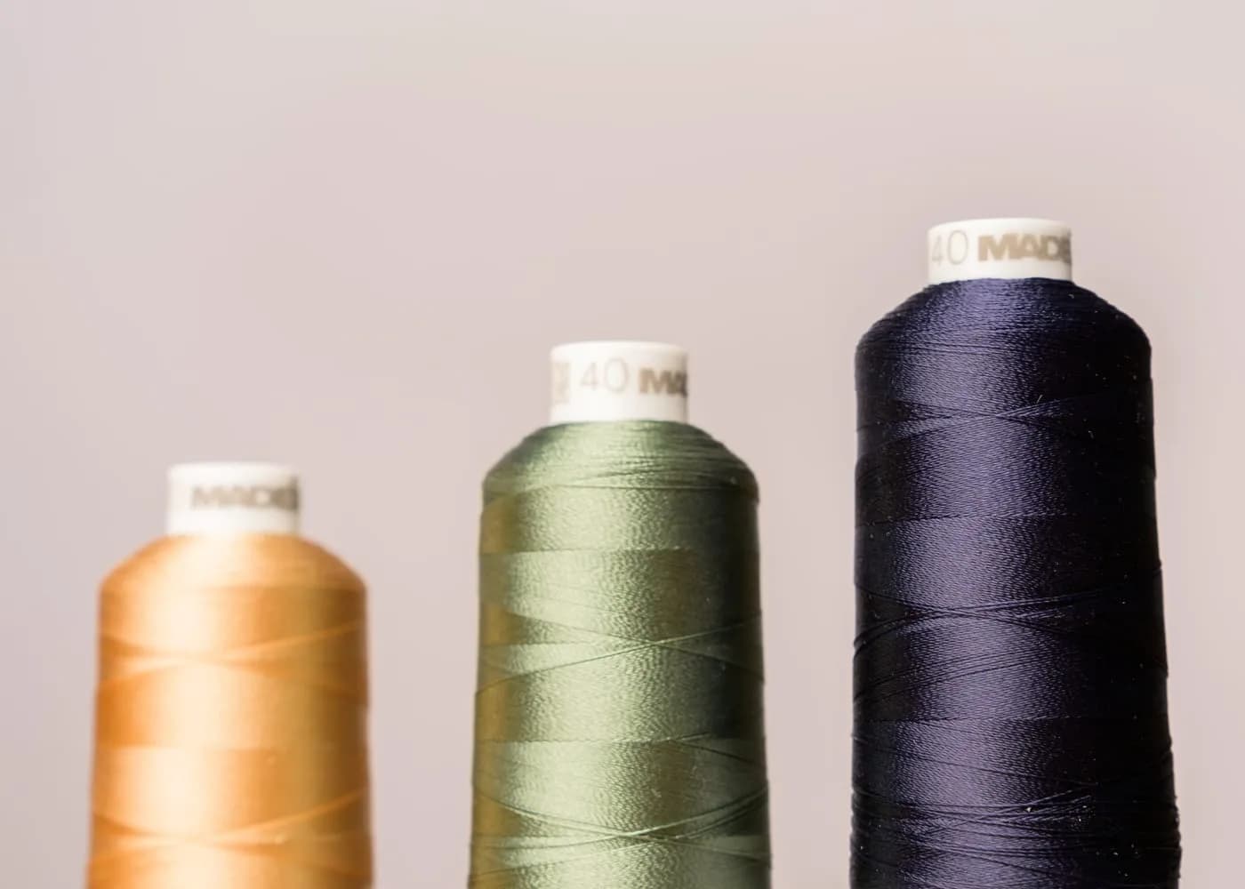 Cones of embroidery thread in gold, sage and navy