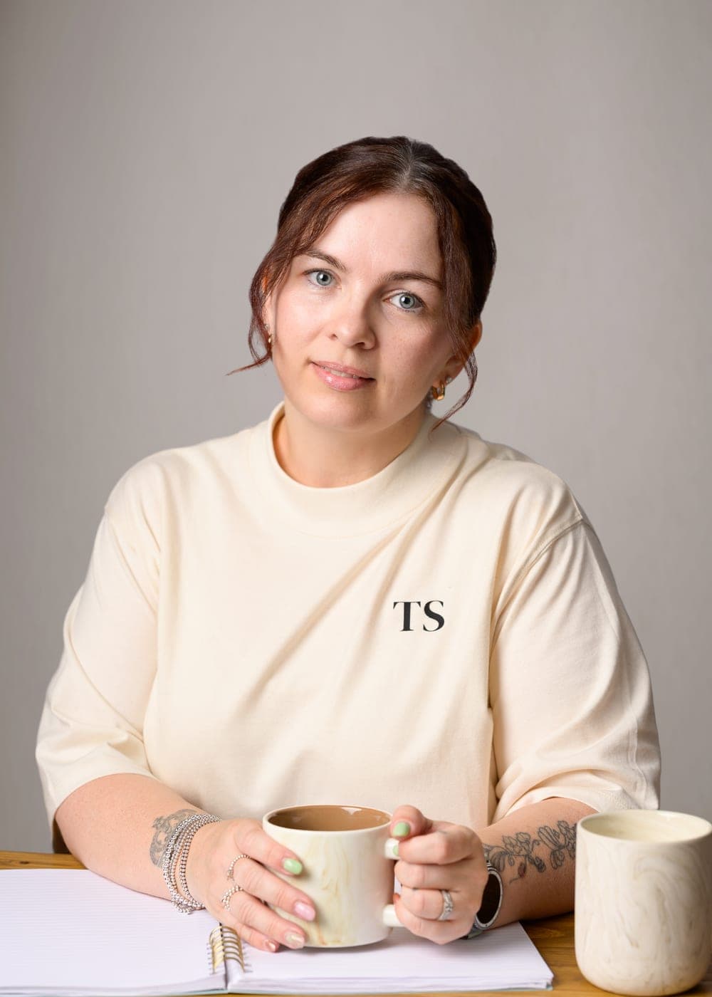 Julie-Anne, founder of Tiny Stitch, at her desk with a cup of coffee
